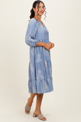 woman wearing a light blue floral print tiered midi dress with three-quarter sleeves and a v-neckline