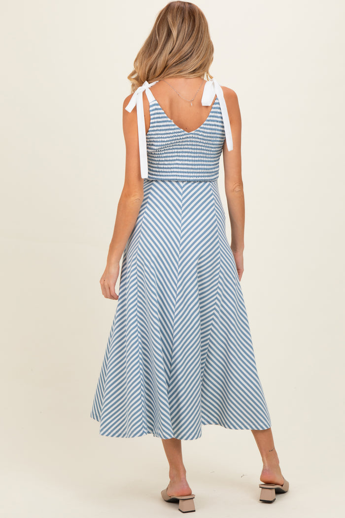 woman wearing a blue and white striped maternity dress with tie straps and a flared skirt, showing her back