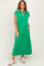 woman wearing a green maxi dress with a collared neckline and white trim, styled with white sneakers