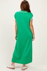 woman wearing a green maxi dress with decorative trim on the sleeves and back, styled casually with white sneakers