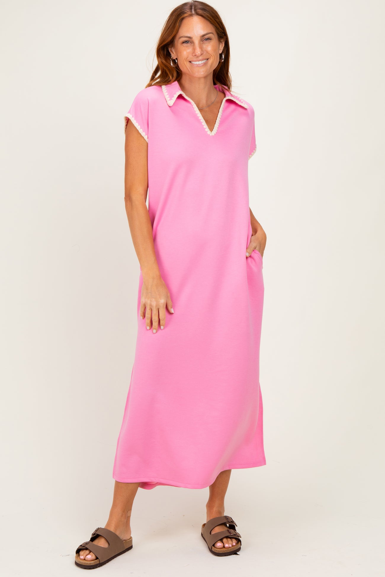 woman wearing a pink short sleeve collared dress with pockets and a relaxed fit