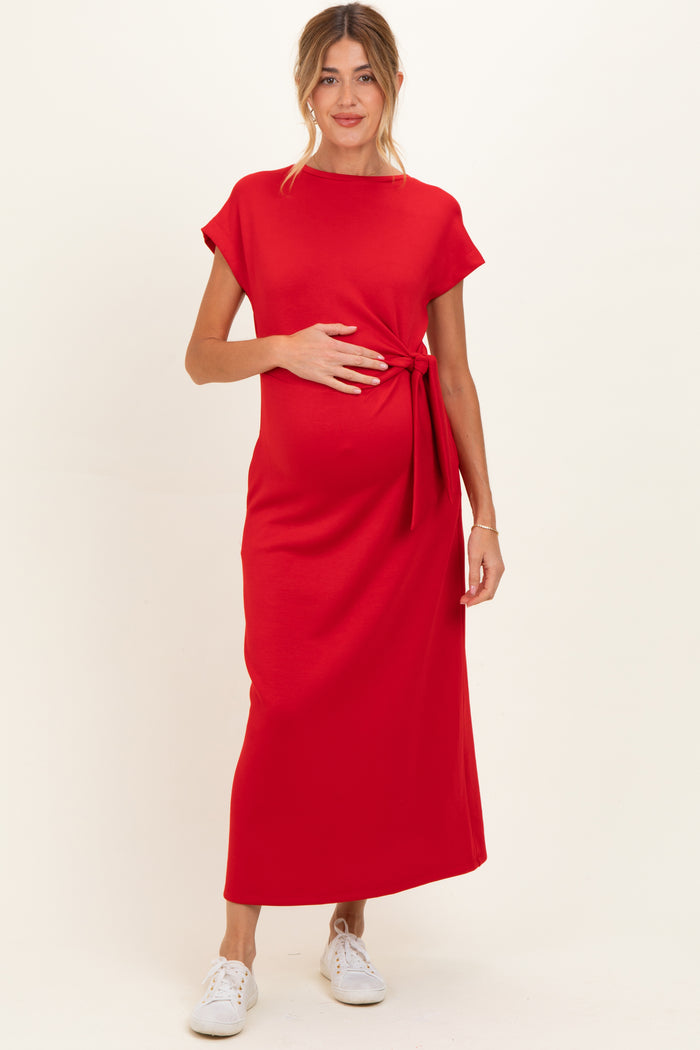 woman wearing a red short sleeve maternity maxi dress and holding her baby bump