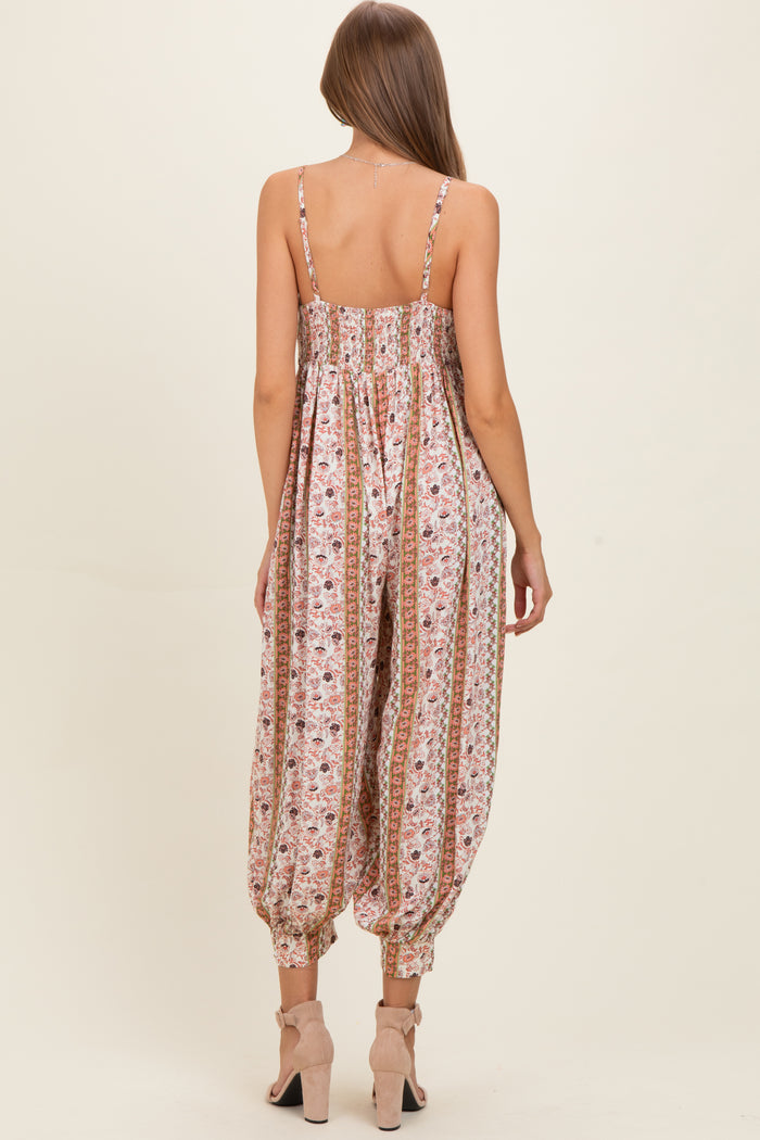 woman wearing a floral print maternity jumpsuit with elastic waistband and tapered legs, showing the back view