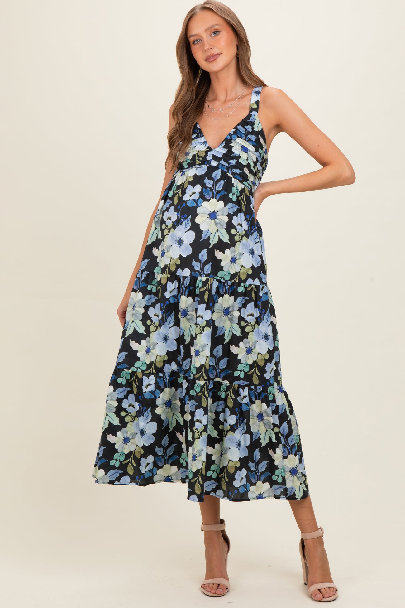 woman wearing a black floral maternity dress with a deep v-neck and tiered skirt, showing her baby bump