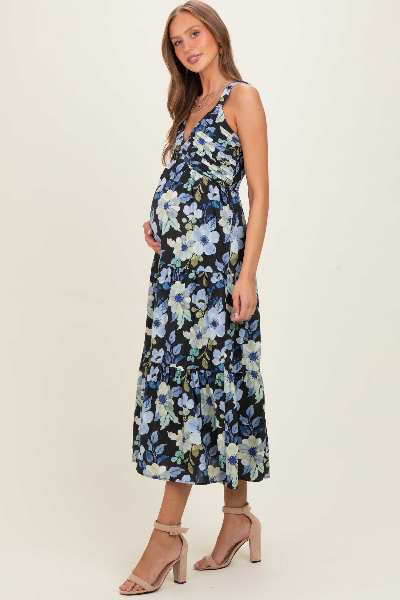 woman wearing a black floral maternity maxi dress with a fitted bodice and tiered skirt, highlighting her baby bump