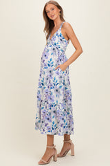 woman wearing a floral print maternity dress with pockets and a baby bump visible, styled with strappy heels