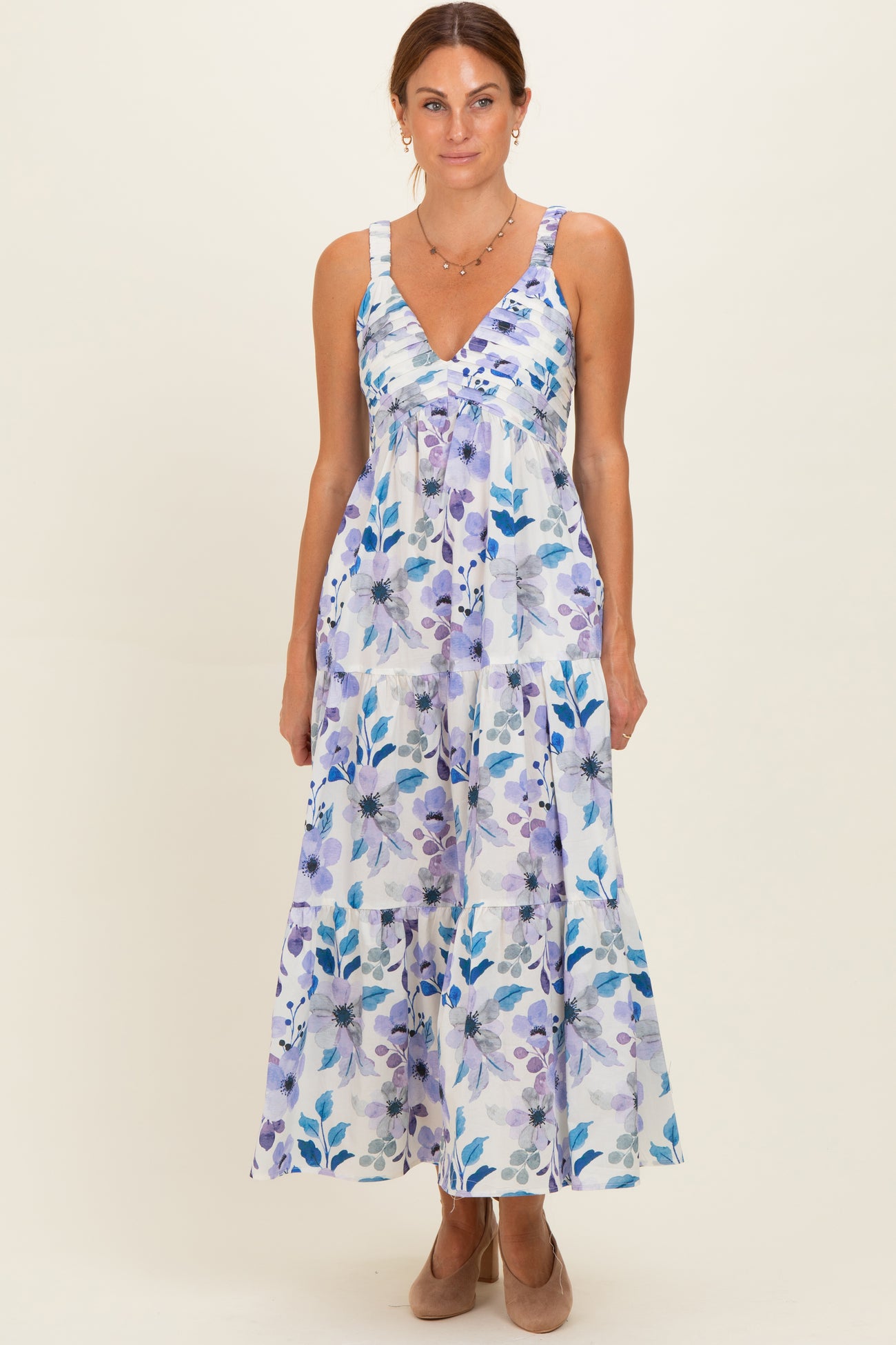 woman wearing a floral maxi dress with purple and blue hues and a v-neckline, standing against a light background