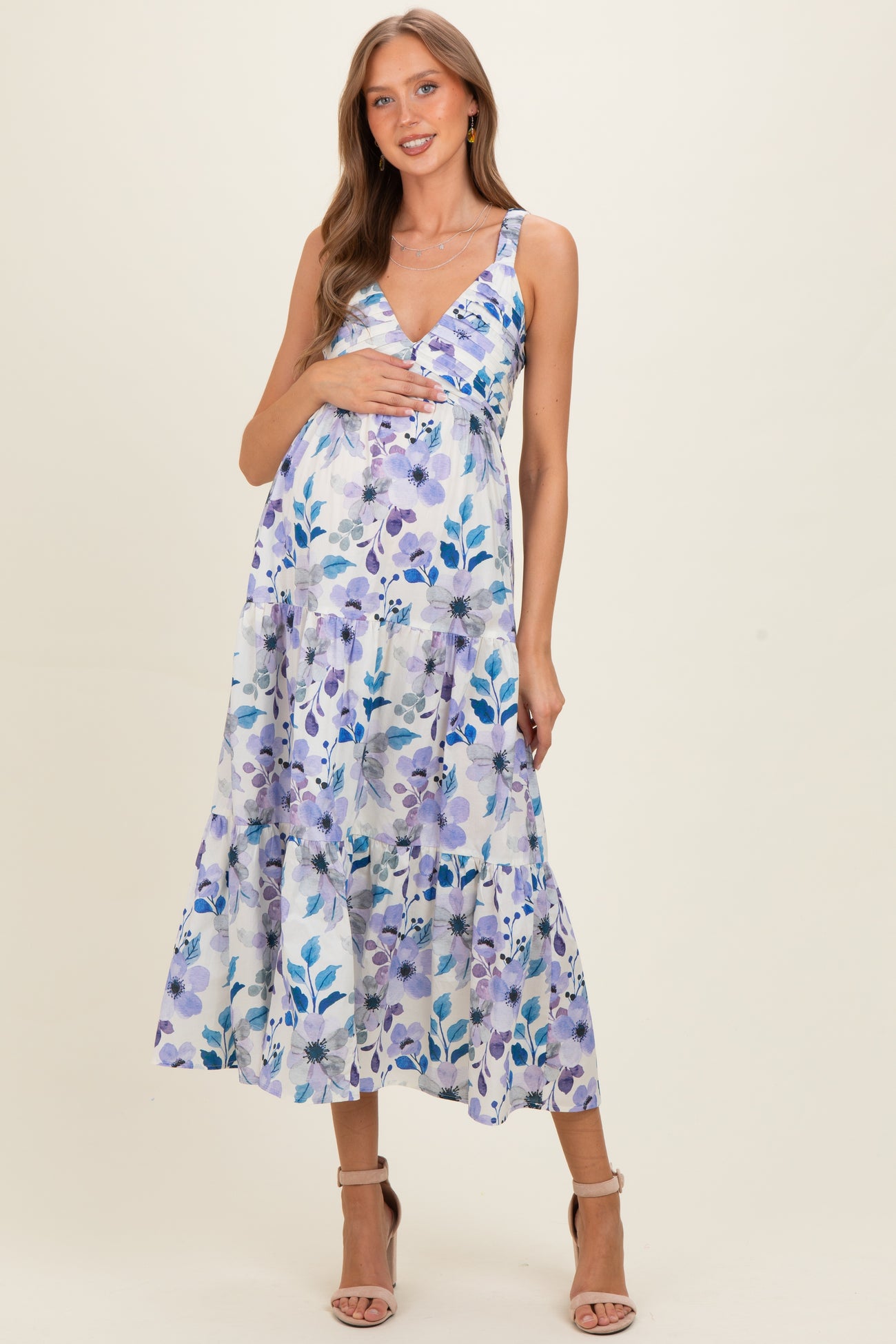woman wearing a floral print maternity midi dress with a v-neck and tiered skirt, holding her baby bump