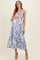 woman wearing a floral print maternity midi dress with a v-neck and tiered skirt, holding her baby bump