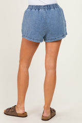 woman wearing light blue denim shorts with an elastic waistband, showing the back view and paired with brown slide sandals