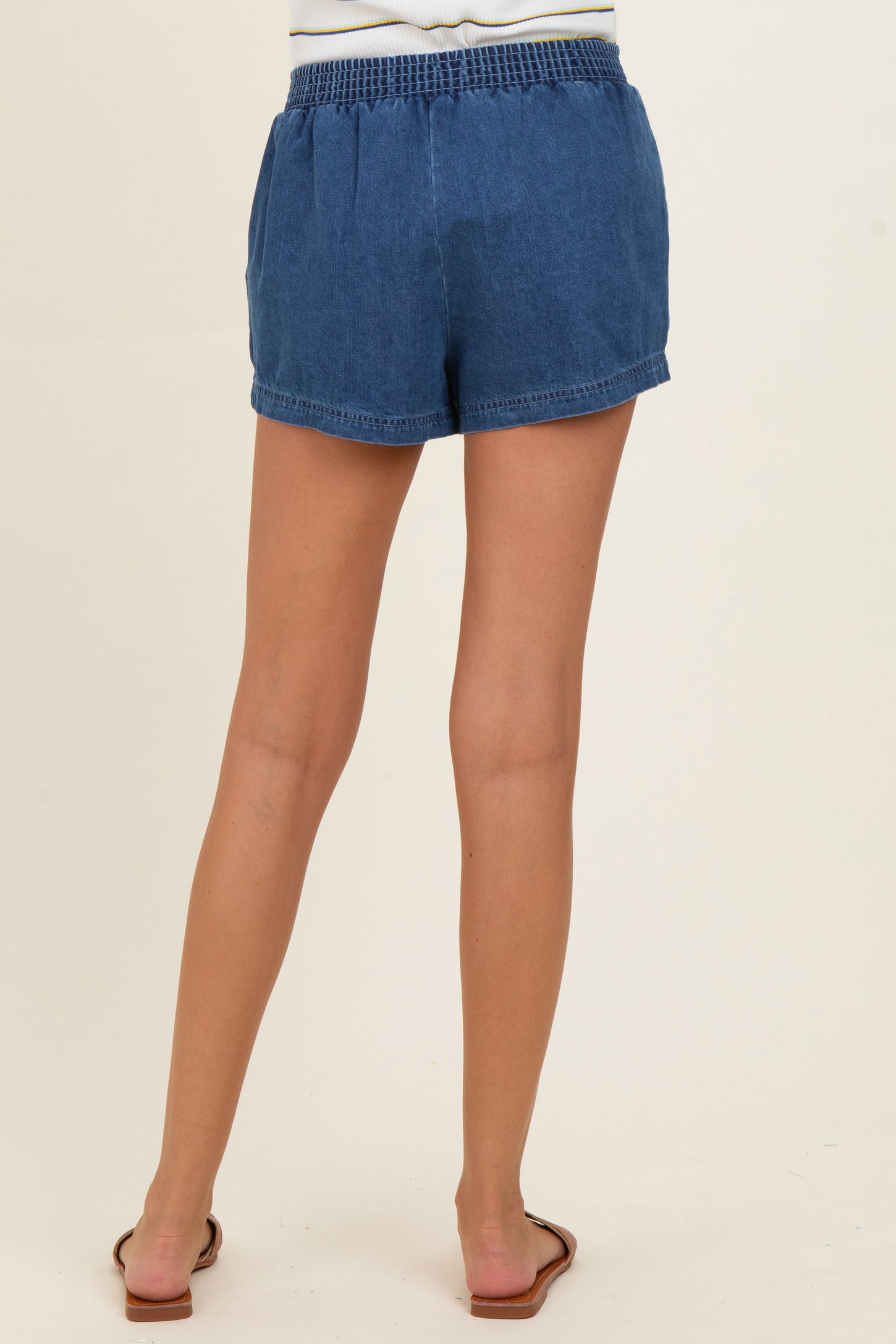 woman wearing blue denim maternity shorts, showing the back view and elastic waistband