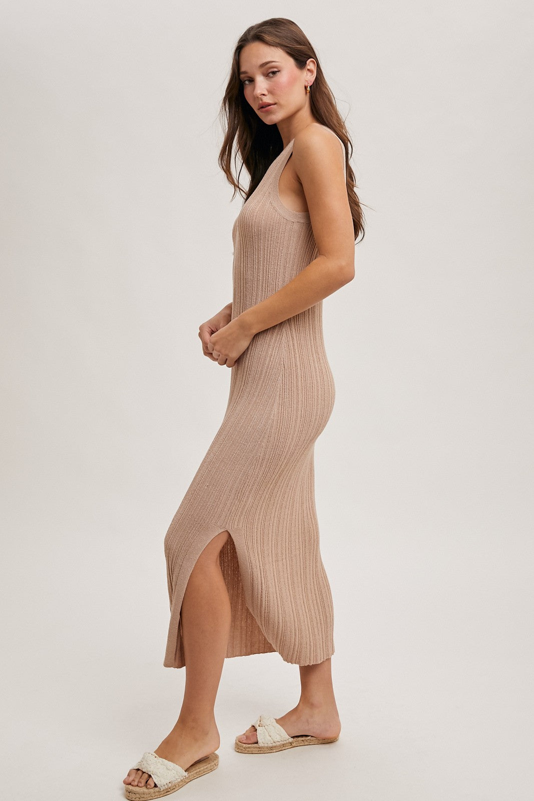 woman wearing a beige ribbed midi dress with a side slit and spaghetti straps