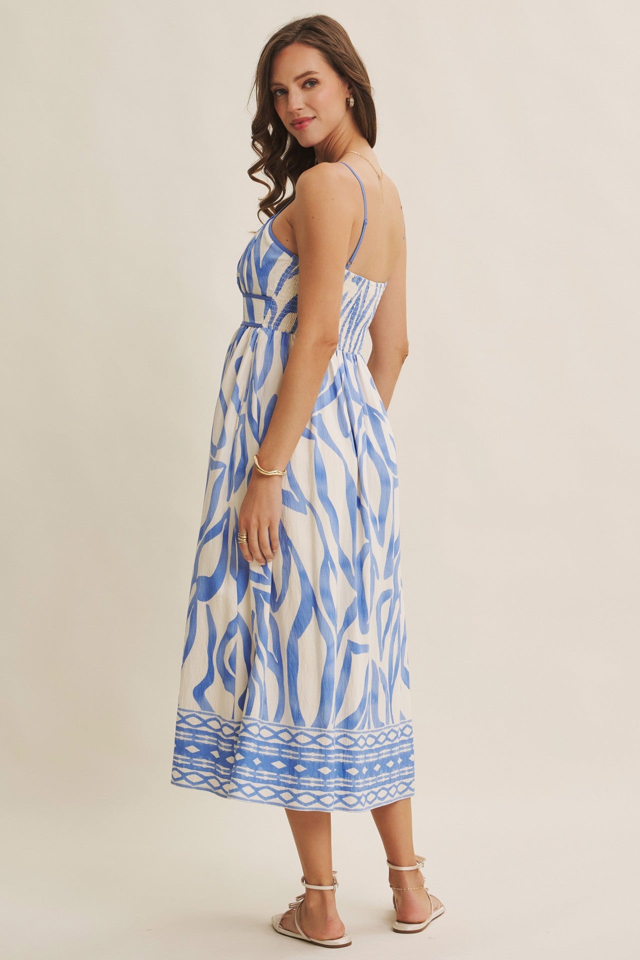 woman wearing a blue and white patterned maxi dress with adjustable straps and a flowing skirt