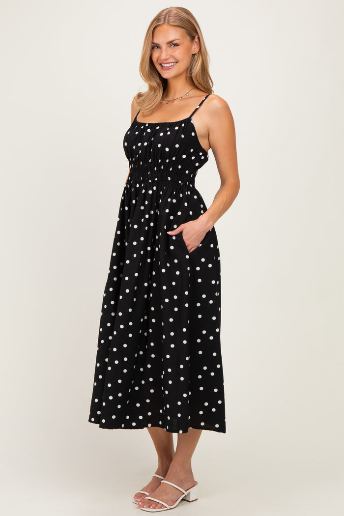 woman wearing a black polka dot midi dress with spaghetti straps and pockets