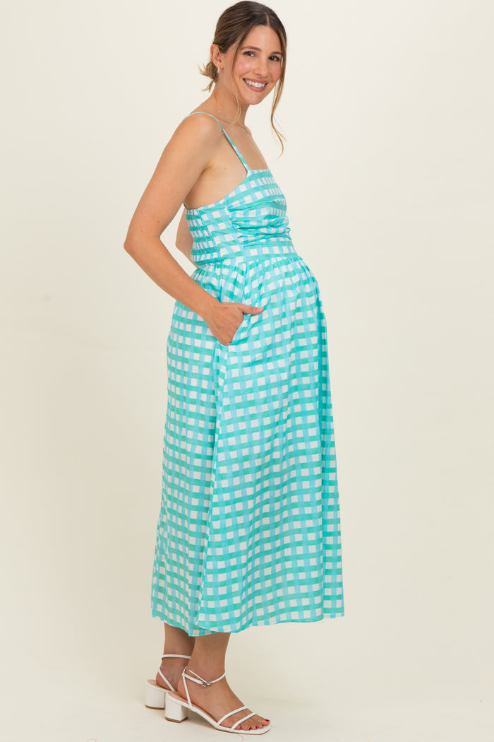 woman wearing a turquoise and white checkered maternity maxi dress with pockets and showing her baby bump