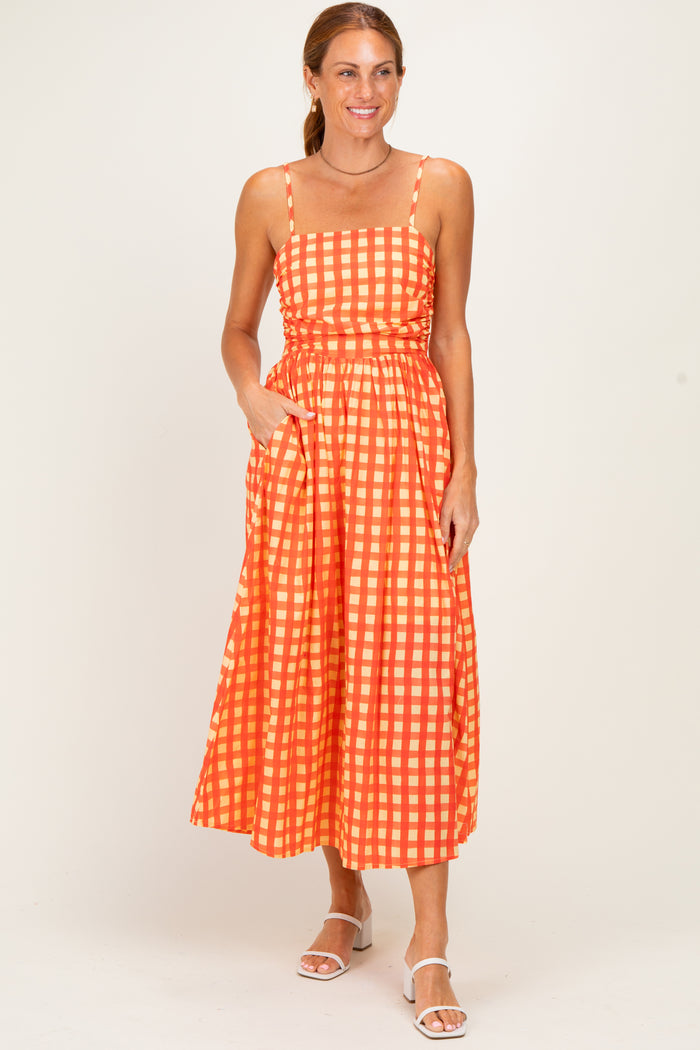 woman wearing an orange and white checked maxi dress with adjustable straps and pockets