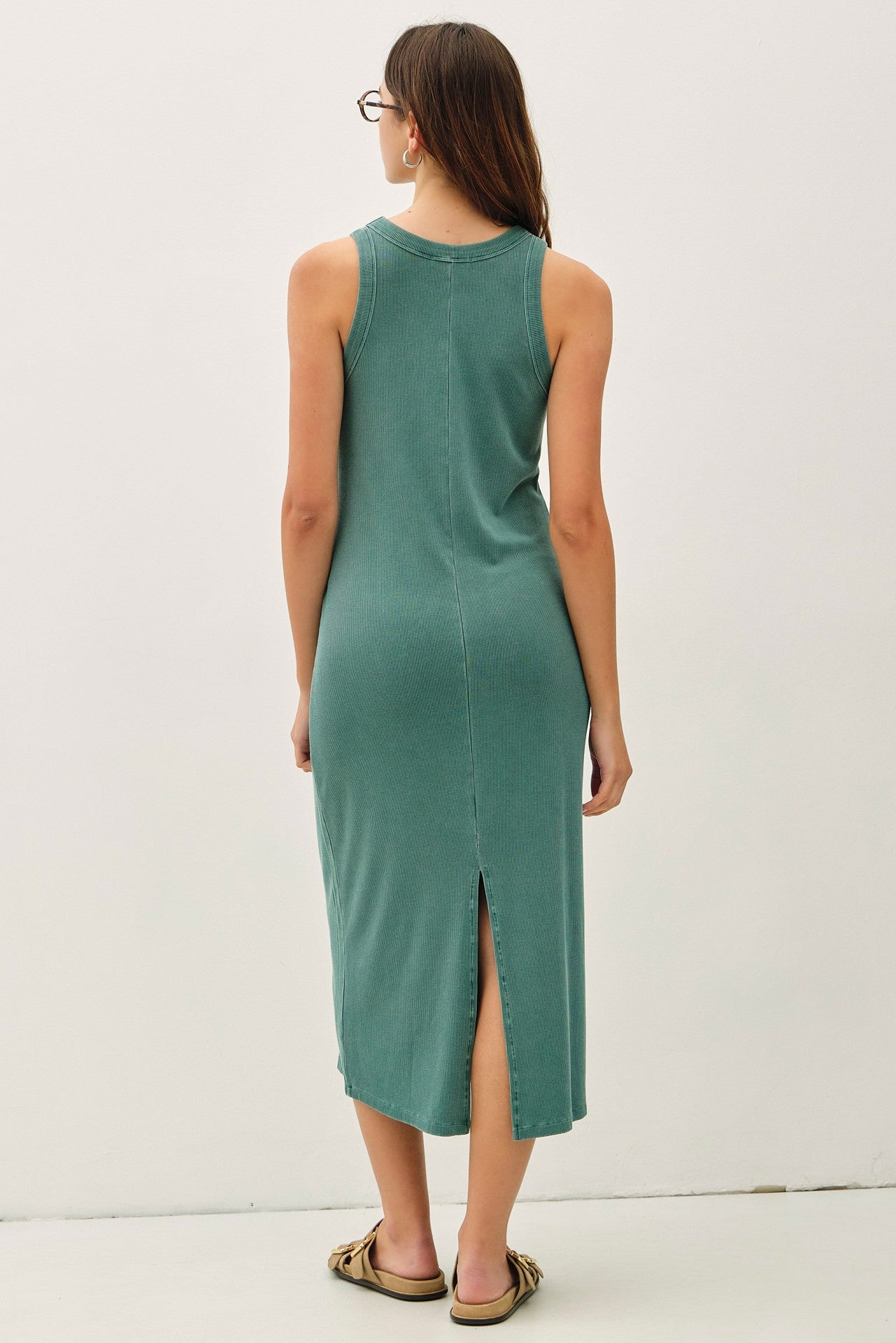 woman wearing a teal sleeveless midi dress with a side slit and a relaxed fit, viewed from the back