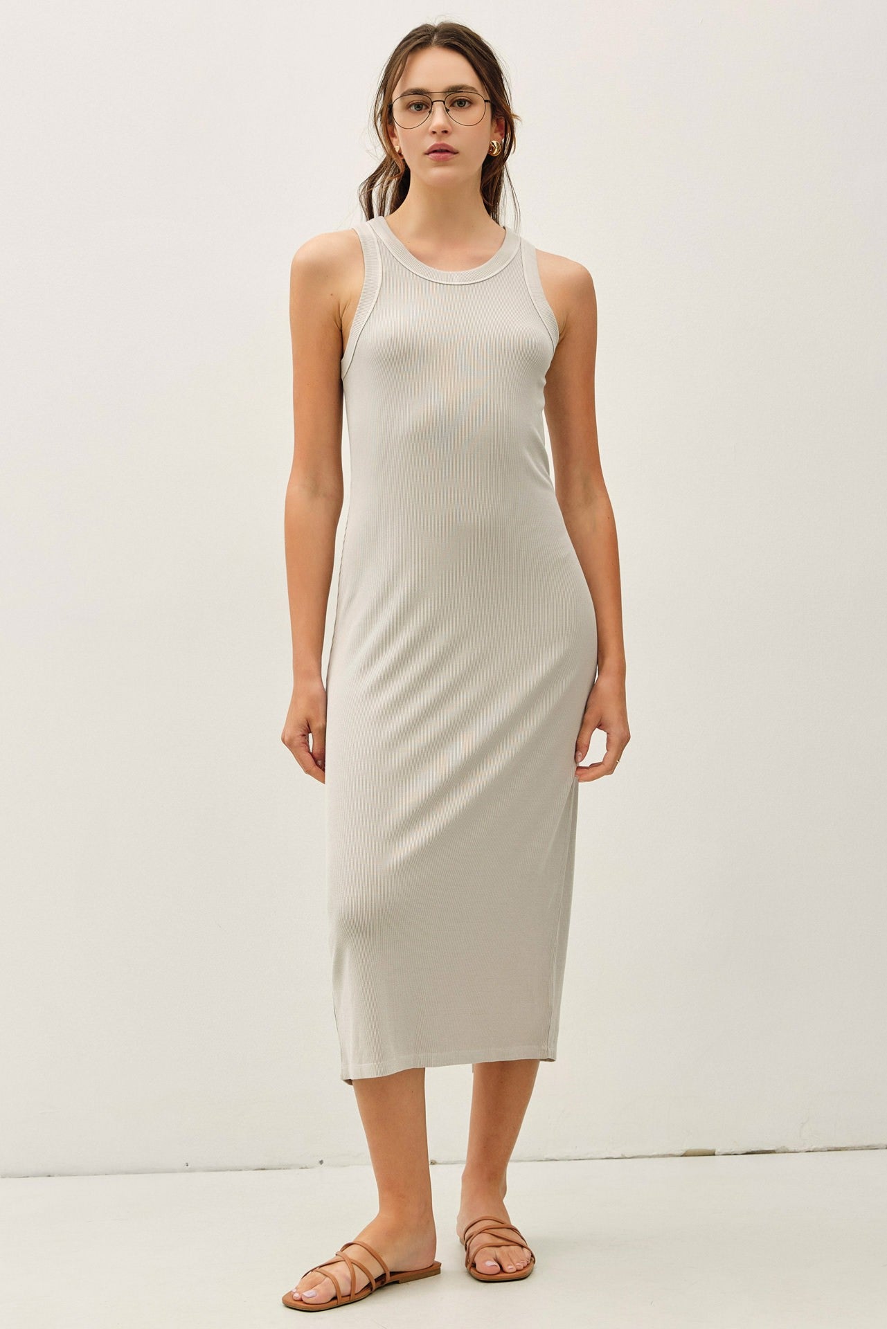 woman wearing a light gray ribbed tank dress that falls below the knee, paired with flat sandals and glasses