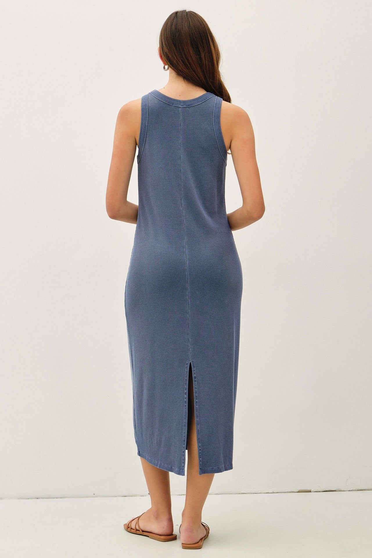 woman wearing a blue sleeveless midi dress with a back slit and a relaxed fit