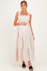 woman wearing a light pink maternity maxi dress with ruffle straps and a smocked bodice, showing her baby bump