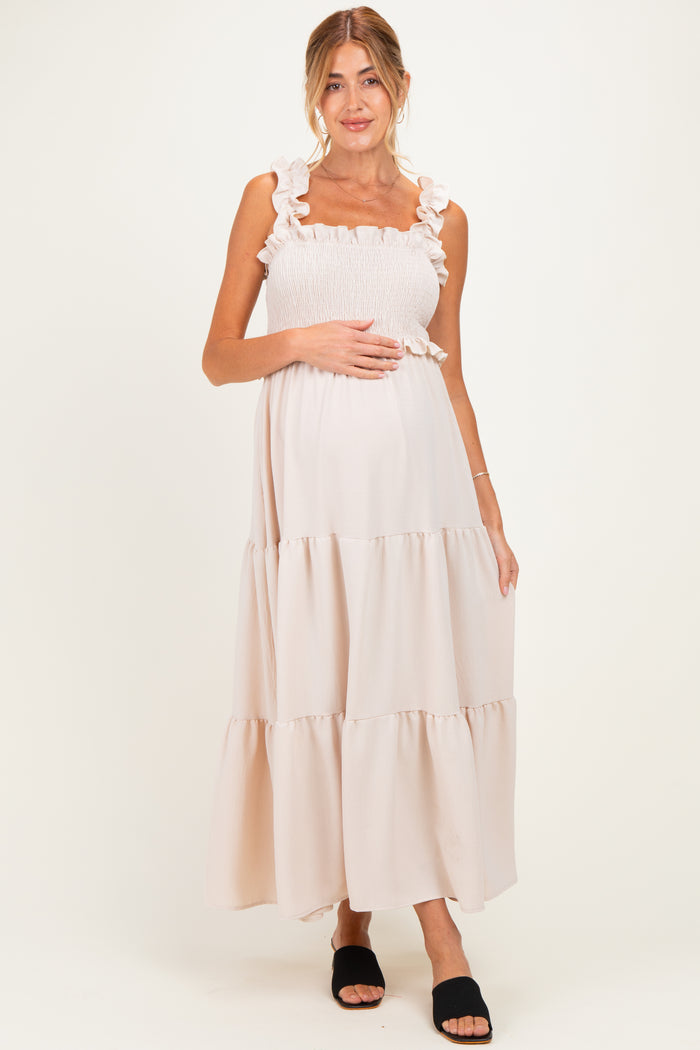 woman wearing a light pink maternity maxi dress with ruffle straps and a smocked bodice, showing her baby bump