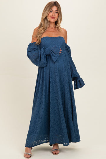 woman wearing a navy blue lace off-the-shoulder maternity dress with puff sleeves and holding her baby bump