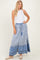 woman wearing a white sleeveless top and a blue patterned maxi skirt with a drawstring waist and tassels