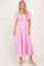 woman wearing a pink maxi dress with puff sleeves and a tie detail at the bust, standing in a light background.