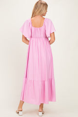 woman wearing a pink maxi dress with flutter sleeves and a tiered hem, shown from the back