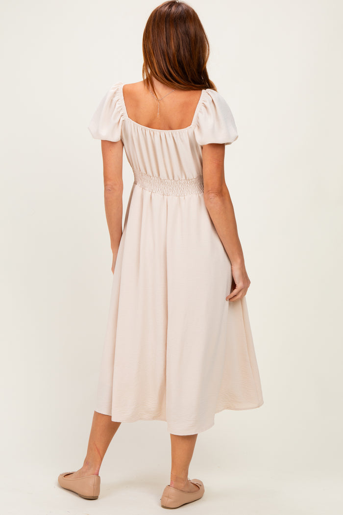 woman wearing a light pink mid-length dress with puff sleeves and smocked bodice, shown from the back