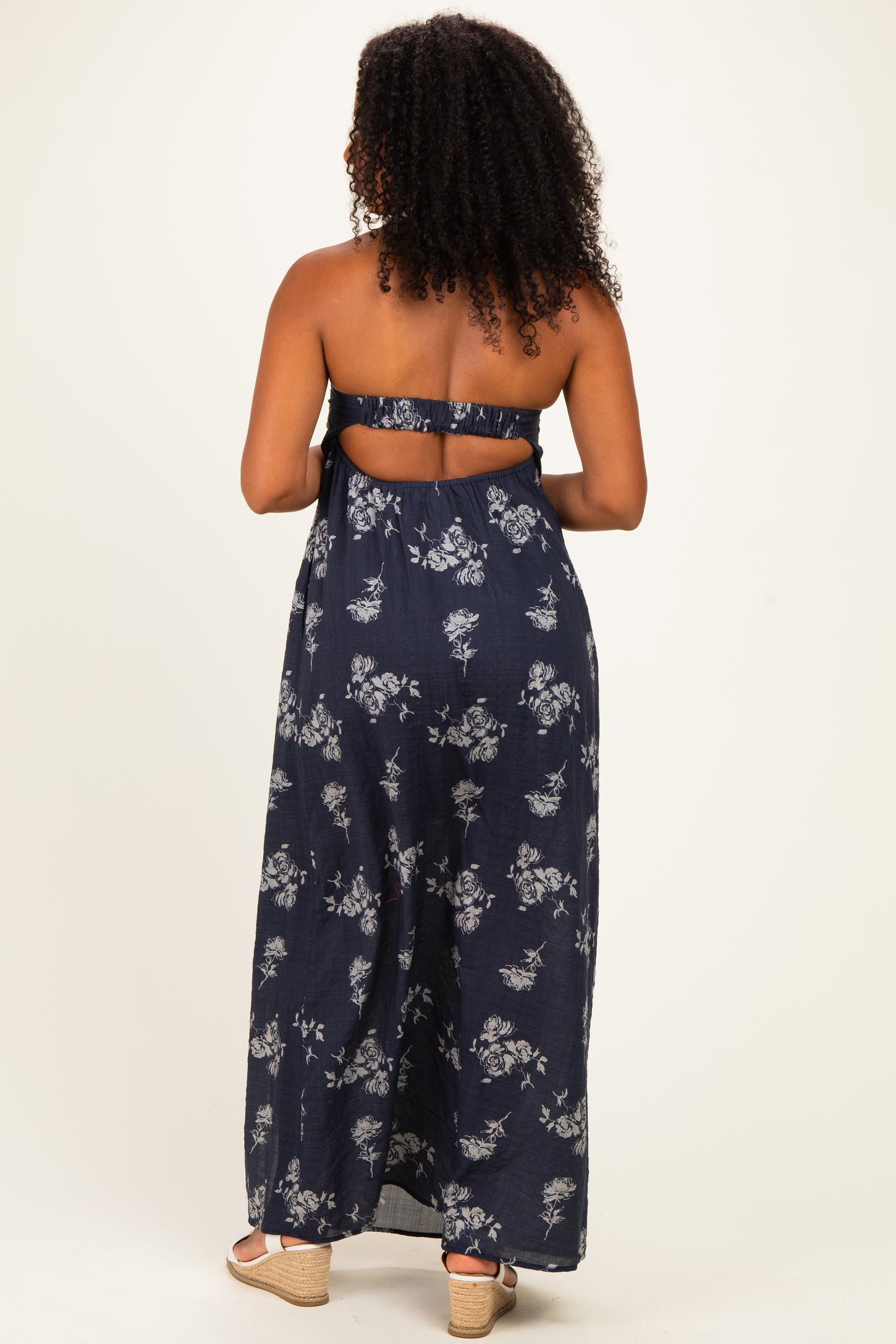 woman wearing a navy blue strapless maxi dress with floral print and an open back detail