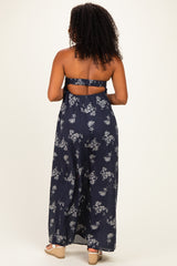 woman wearing a navy blue strapless maxi dress with floral print and an open back detail