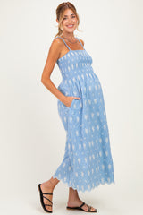 woman wearing a light blue maternity maxi dress with floral patterns and pockets, showcasing her baby bump