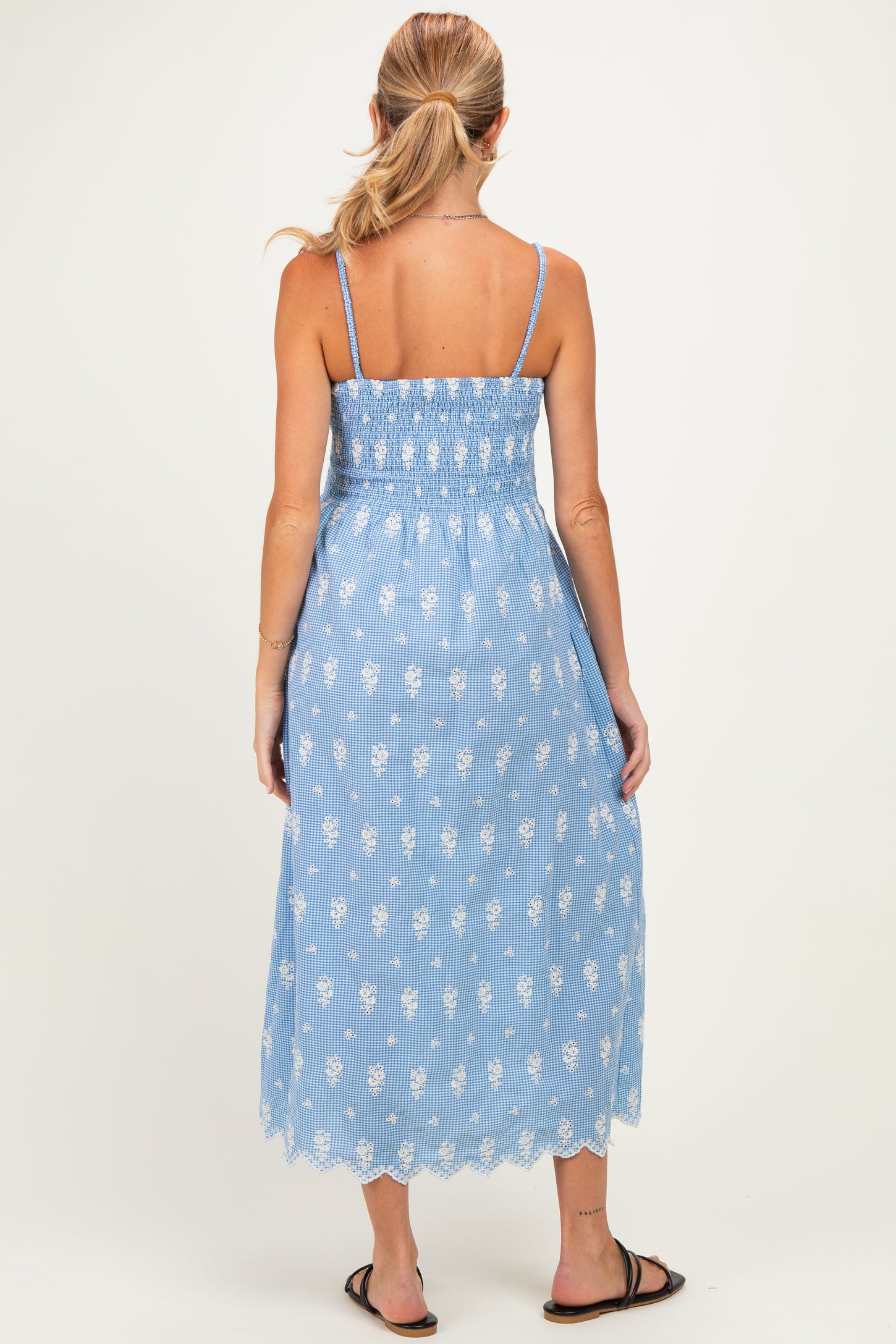 woman wearing a blue maternity dress with floral print and smocked bodice, showing a gathered back and mid-length style