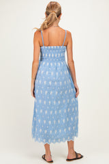 woman wearing a blue maternity dress with floral print and smocked bodice, showing a gathered back and mid-length style
