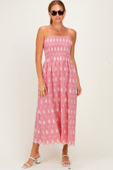 woman wearing a pink sleeveless maxi dress with floral embroidery and a smocked bodice, paired with sunglasses and white sandals