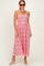 woman wearing a pink sleeveless maxi dress with floral embroidery and a smocked bodice, paired with sunglasses and white sandals