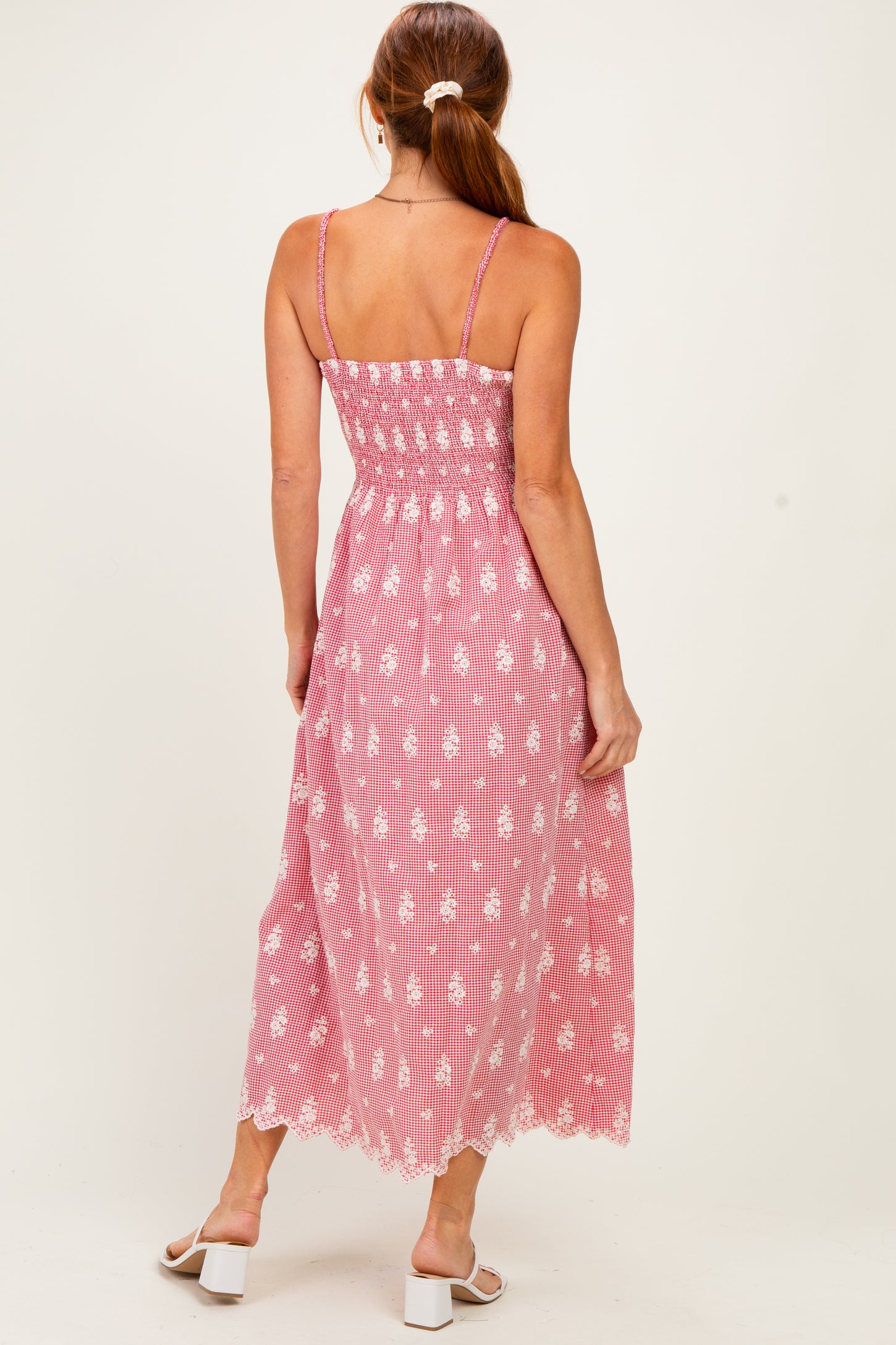 woman wearing a pink and white floral maxi dress with a smocked back and lace hem, standing with her back to the camera