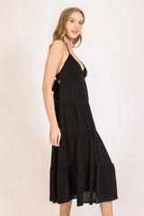 woman wearing a black tiered maxi dress with a halter neckline and open back