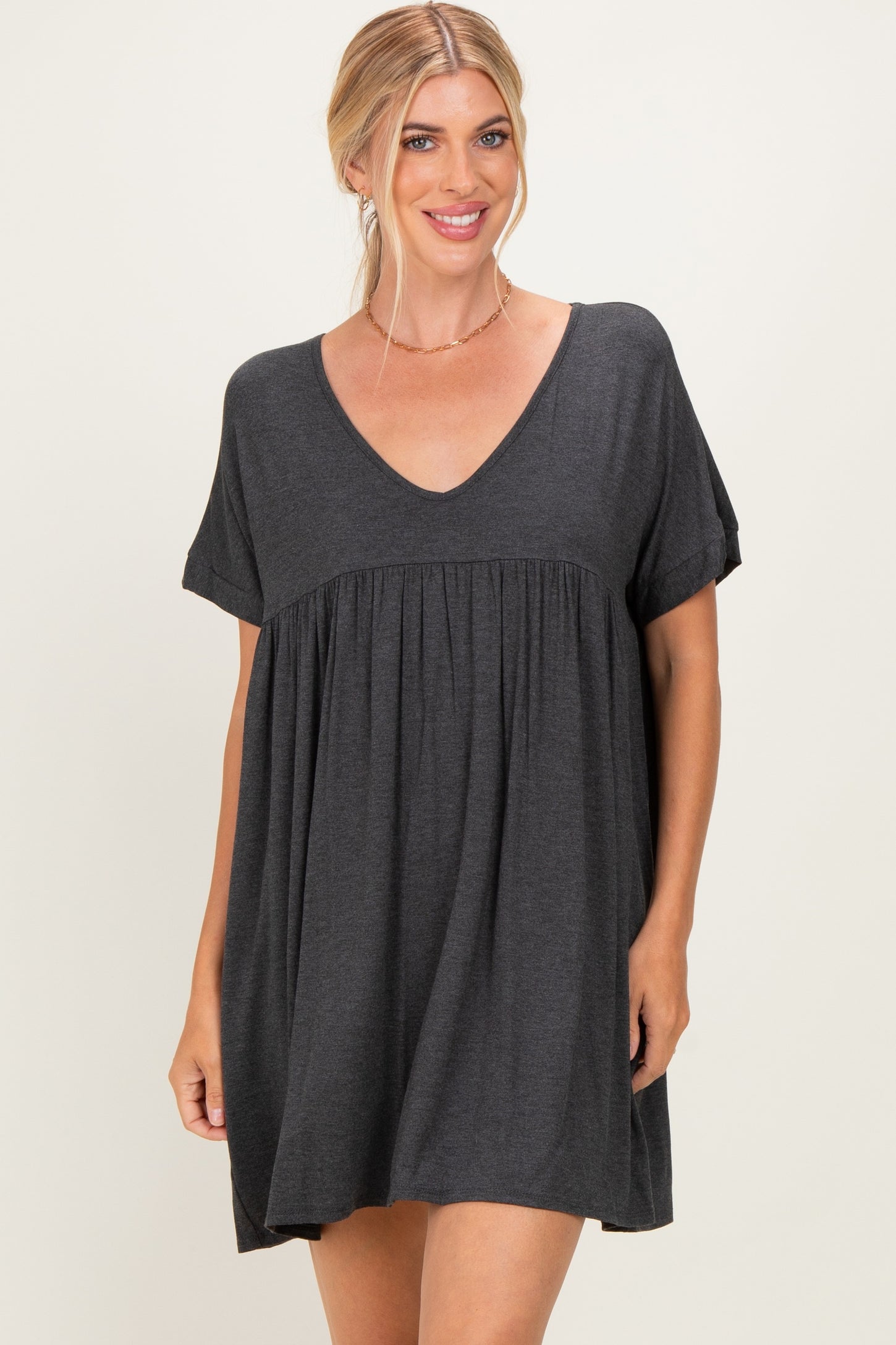 woman wearing a dark gray short sleeve tunic dress with a v-neck and gathered waistline