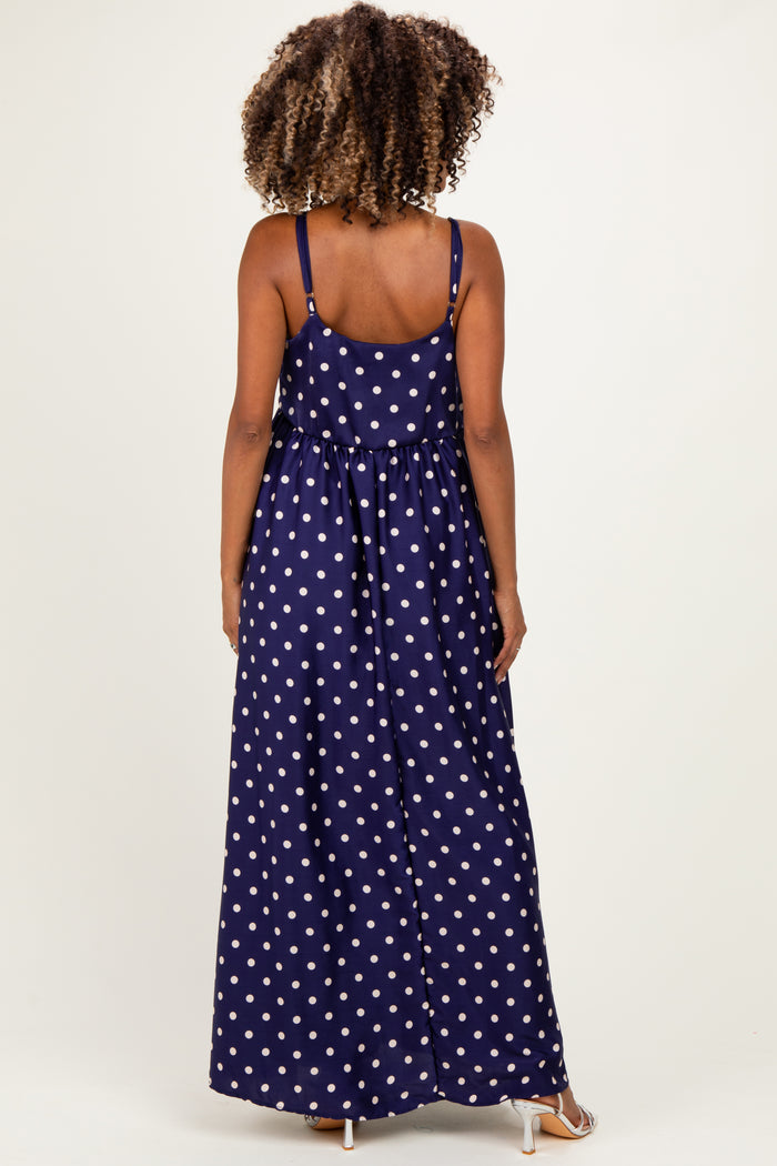 woman wearing a navy blue polka dot maxi maternity dress, showing the back view and adjustable straps