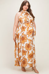 woman wearing a floral halter neck maternity plus maxi dress with a tied waist and a flowy silhouette