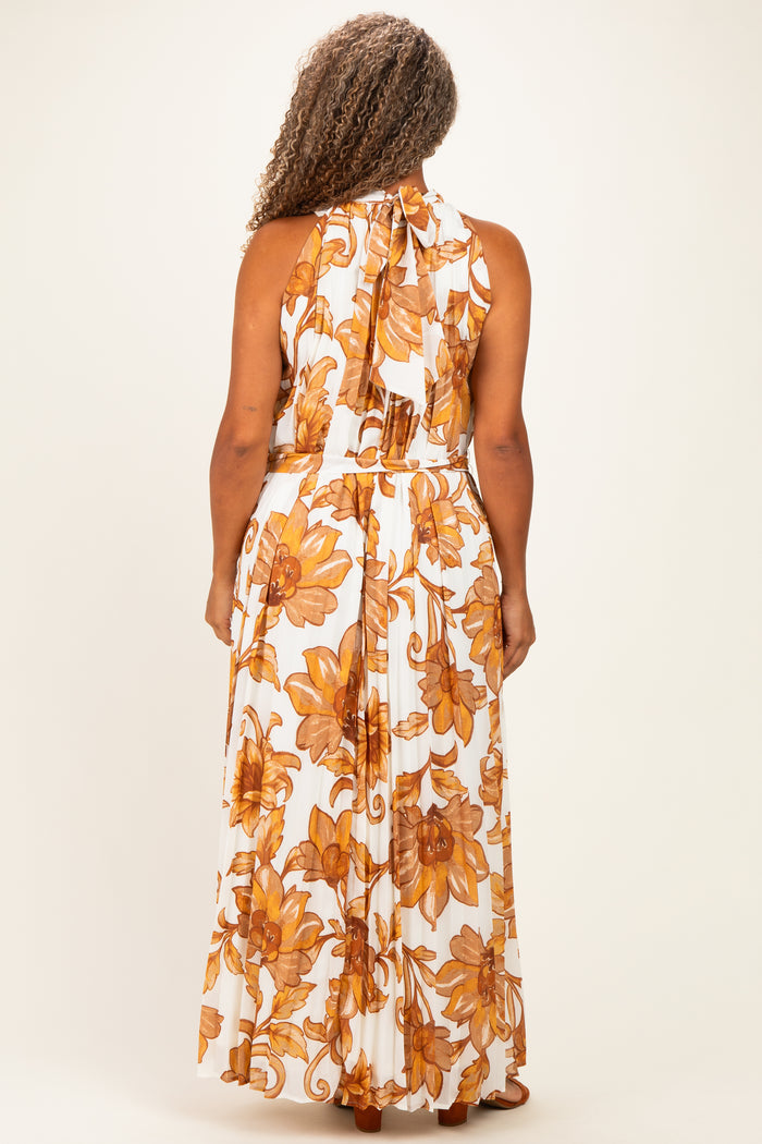 woman wearing a white maxi dress with large orange floral patterns and a halter neck, seen from the back
