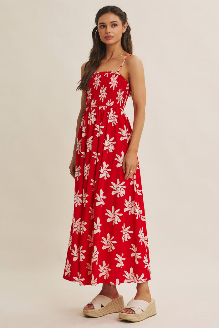 woman wearing a red floral maxi dress with spaghetti straps and a tiered skirt