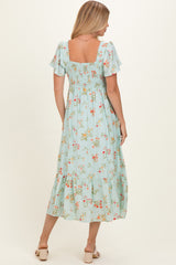 woman wearing a light blue floral maxi dress with short ruffled sleeves and a smocked bodice, viewed from the back