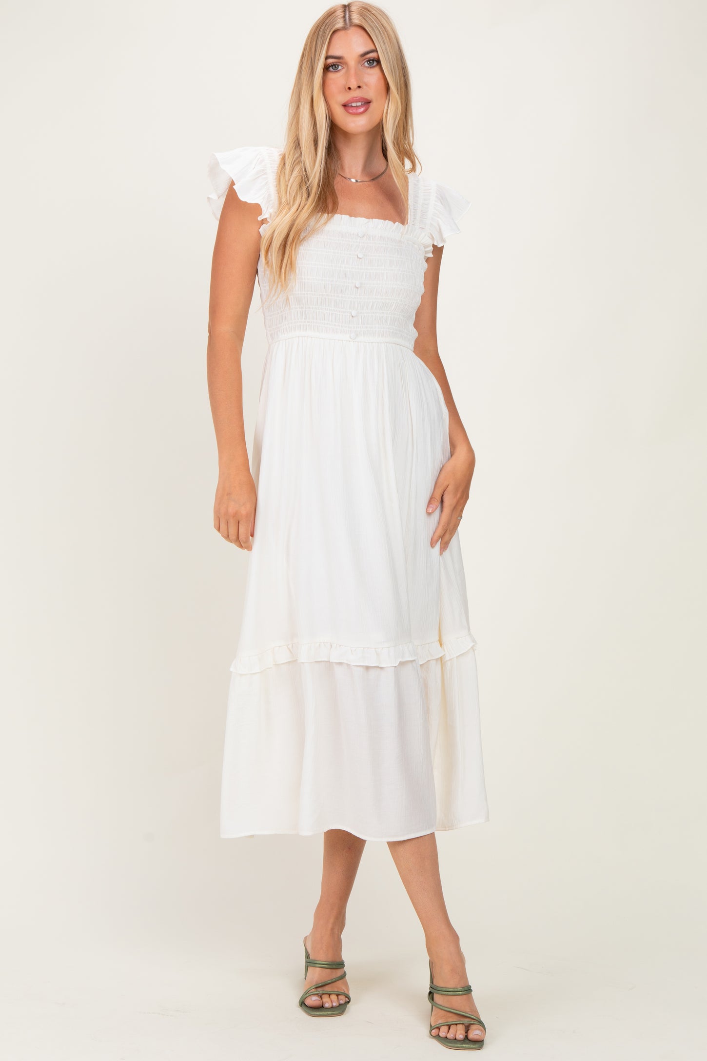woman wearing a white smocked maxi dress with ruffle sleeves and a tiered skirt