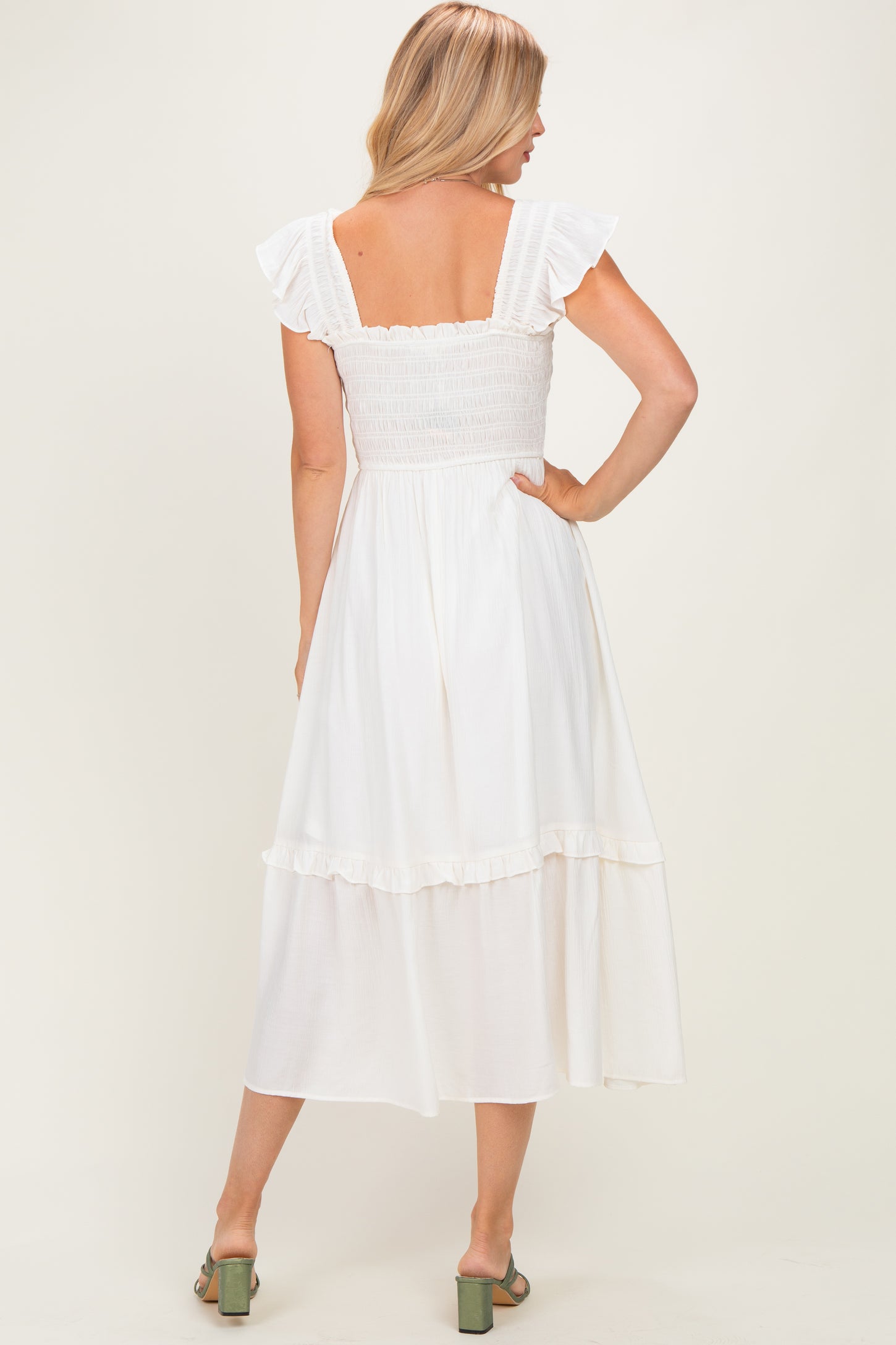 woman wearing a white midi dress with ruffled sleeves and a smocked bodice, showing the back view