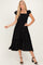woman wearing a black midi dress with ruffled sleeves and a smocked bodice, posing with one hand on her hip