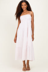 woman wearing a light pink tiered maxi dress with spaghetti straps and a smocked bodice