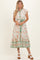 woman wearing a floral midi dress with cap sleeves and a tie waist in shades of orange and green